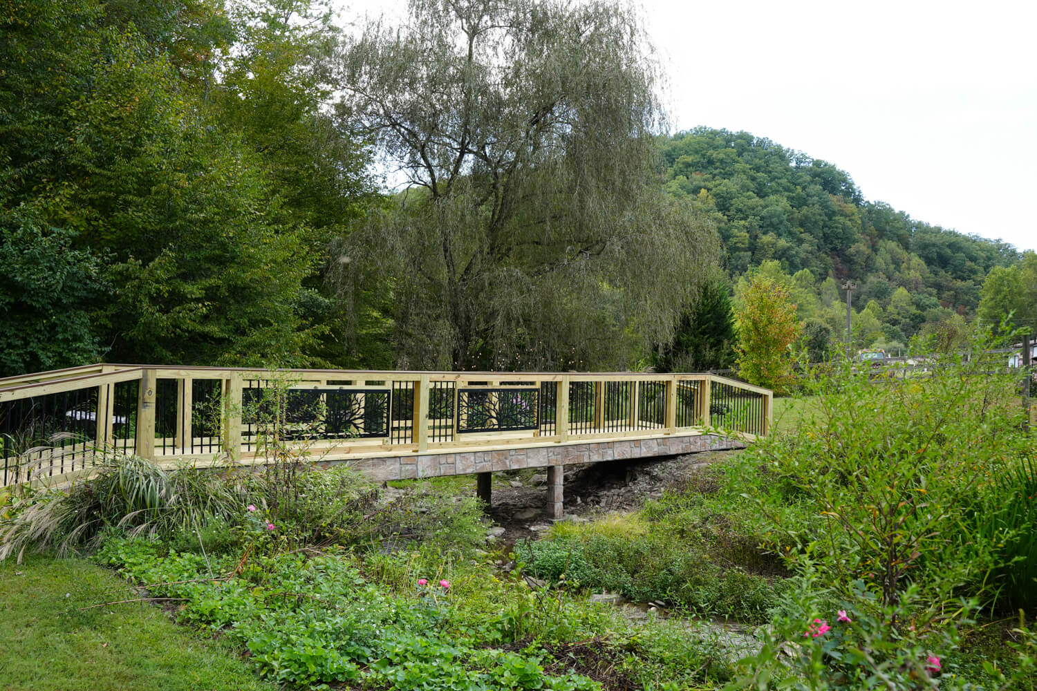 long wooden bridge with black iron willow tree peanels over a creek by a mountain ridge at a wedding venue in Pigeon Forge Tennessee