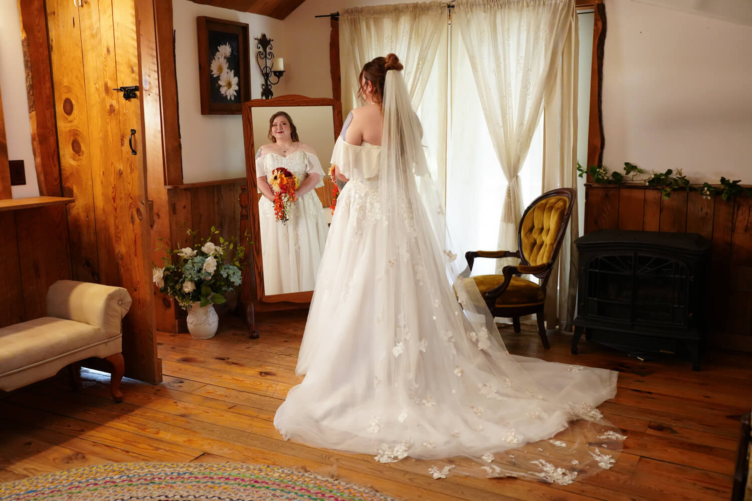 Bride looking into a full length wooden mirror in her dressing room at the Honeysuckle Hills barn wedding venue in Pigeon Forge