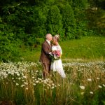 Groom kissing his bride's forehead in a field of daisies at the mountain adventure site at Honeysuckle Hills in Pigeon Forge