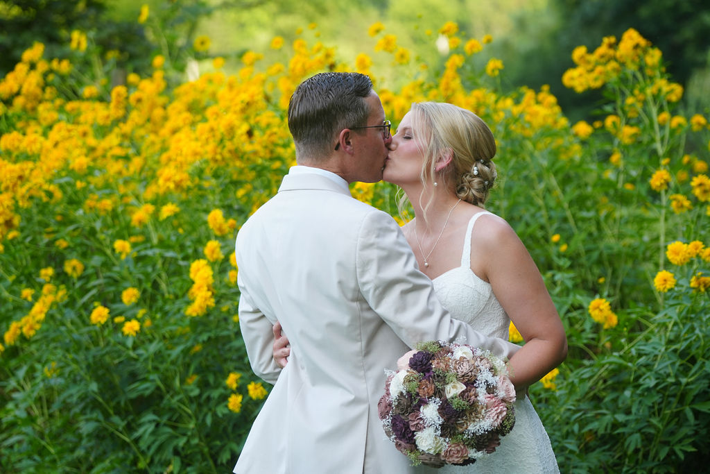 Wedding couple kissing the summer gardens at Honeysuckle Hills with yellow rudbekia in bloom