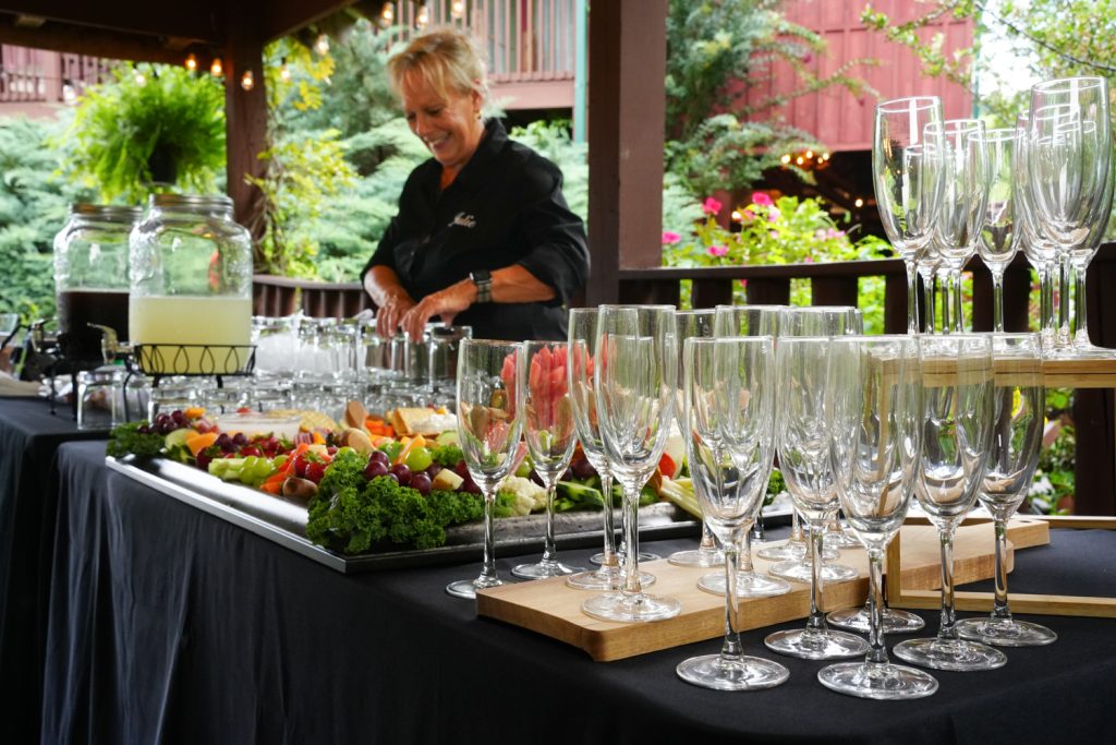 Bartender preparing a charcuterie board with mocktails served in upscale glassware in the creekside pavilion at Honeysuckle Hills
