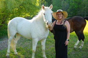 Regina Starkey, owner of Honeysuckle Hills wedding venue, standing with her horse named Sugar